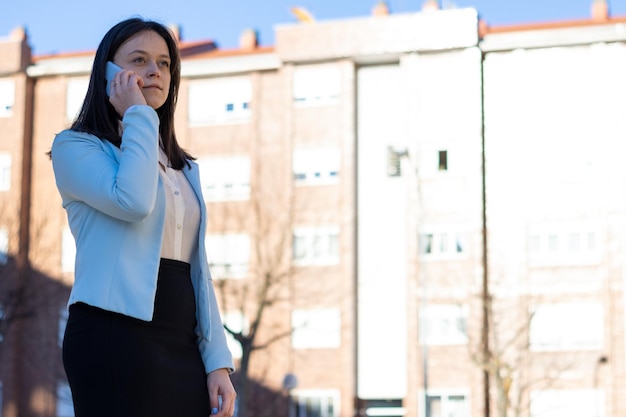 Portrait d'une jeune femme d'affaires caucasienne parlant au téléphone dans la rue