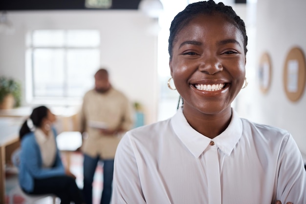 Portrait d'une jeune femme d'affaires confiante travaillant dans un bureau moderne avec ses collègues en arrière-plan