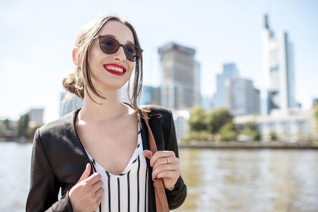 Portrait de la jeune femme d'affaires à l'extérieur sur le fond des gratte-ciel de Francfort