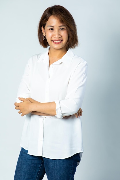 Portrait de jeune femme d'affaires gaie assez mignonne asiatique gardant les bras croisés et souriant de près et regardant la caméra sur fond blanc. maquillage naturel et dents blanches