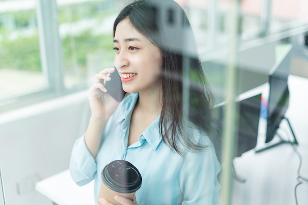 Portrait d'une jeune femme d'affaires heureuse parlant au téléphone