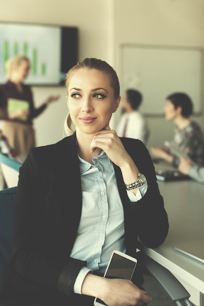 portrait d'une jeune femme d'affaires à l'intérieur d'un bureau de démarrage moderne, équipe dans un groupe de réunion en arrière-plan