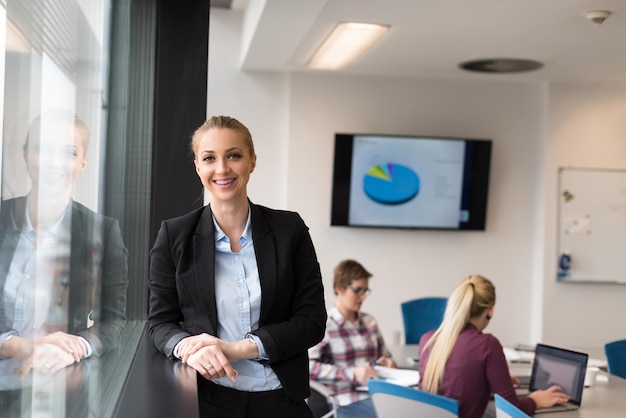 portrait d'une jeune femme d'affaires à l'intérieur d'un bureau de démarrage moderne, équipe dans un groupe de réunion en arrière-plan