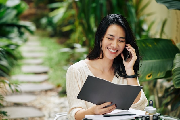 Portrait d'une jeune femme d'affaires joyeuse lisant un catalogue et commandant des ingrédients pour la marque de cosmétiques sur laquelle elle travaille