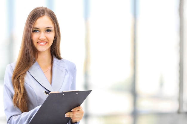 Portrait d'une jeune femme d'affaires mignonne souriante dans un environnement de bureau