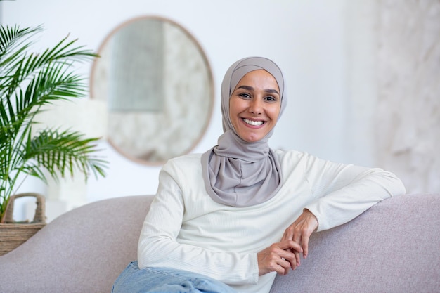Portrait de jeune femme d'affaires d'origine orientale en hijab assise sur un canapé à la maison et regardant