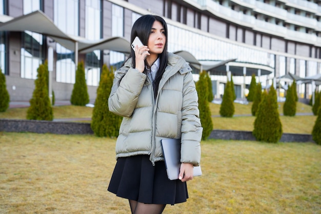 Portrait d'une jeune femme d'affaires parlant au téléphone dans la rueBusiness traite la gestion d'équipe à distance