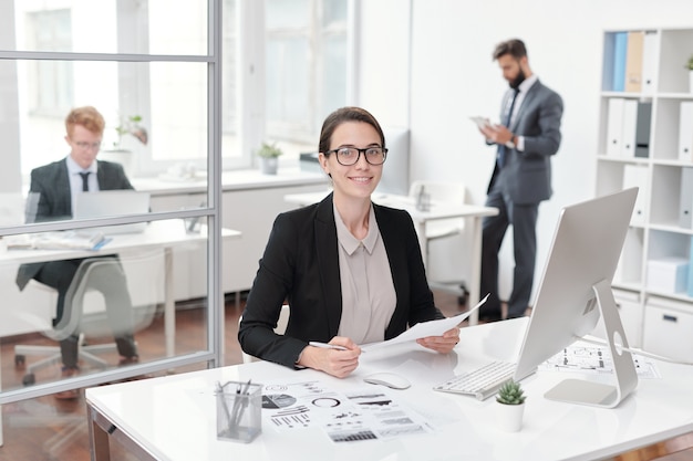 Portrait de jeune femme d'affaires portant des lunettes souriant alors qu'il était assis au bureau dans le concept de bureau, comptable ou gestionnaire