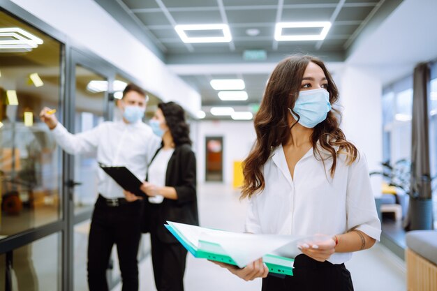 Portrait d'une jeune femme d'affaires portant un masque protecteur dans un couloir d'immeuble de bureaux.