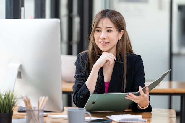 Portrait d'une jeune femme d'affaires réussie assise à son bureau travaillant sur un ordinateur de bureau dans un bureau ouvert