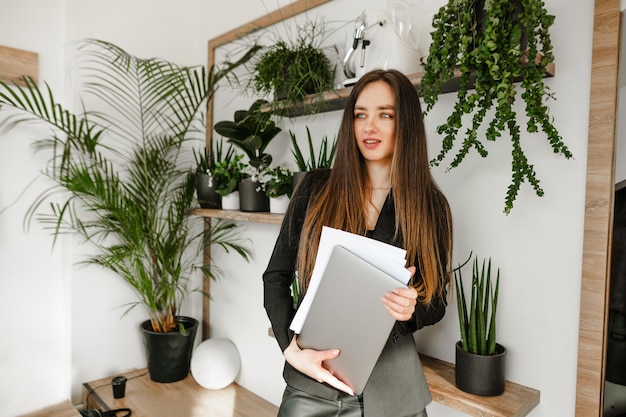 Portrait d'une jeune femme d'affaires séduisante en vêtements formels debout à l'intérieur avec des plantes