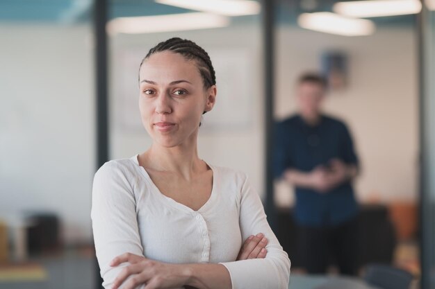 Portrait d'une jeune femme d'affaires souriante dans un bureau de démarrage de coworking à espace ouvert créatif. Femme d'affaires prospère debout au bureau avec fond. Collègues travaillant en arrière-plan.