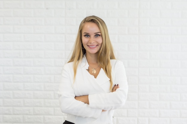 Photo portrait d'une jeune femme d'affaires souriante debout contre un mur de briques blanches