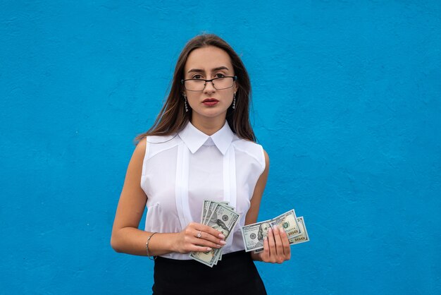 Portrait de jeune femme d'affaires de succès tenir beaucoup de billets d'un dollar d'argent isolés sur bleu