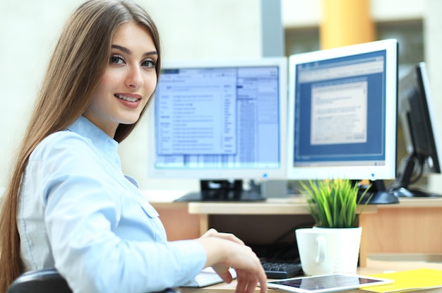 Photo portrait d'une jeune femme d'affaires utilisant un ordinateur au bureau.