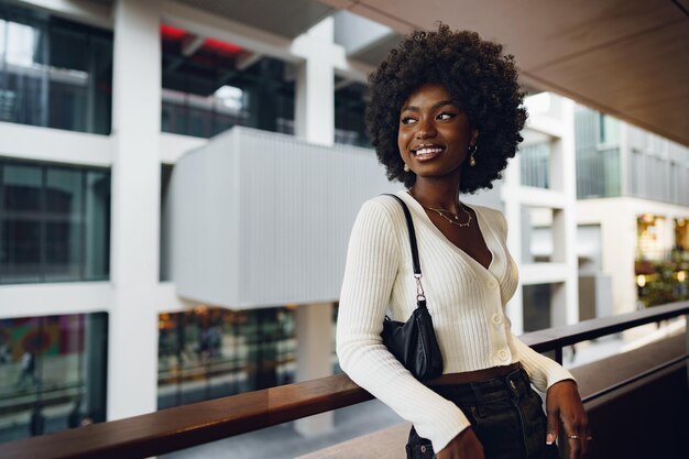 Portrait de jeune femme africaine avec une coiffure debout au balcon et posant