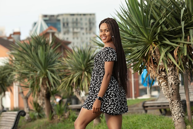 Portrait d'une jeune femme africaine souriante avec des nattes dreadlockées sur la tête.