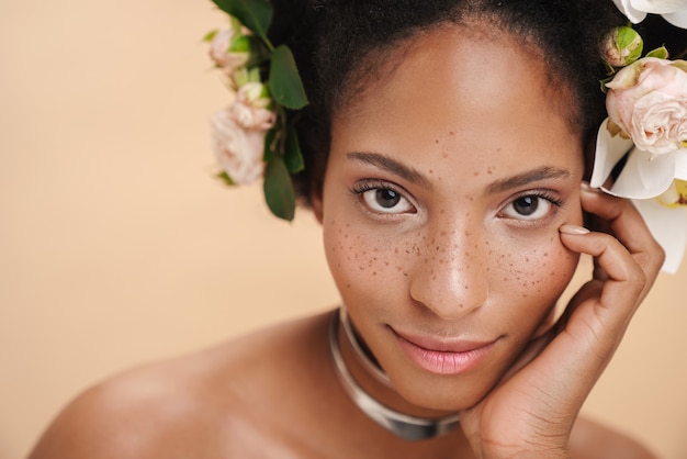 Portrait de jeune femme afro-américaine aux taches de rousseur à moitié nue avec des fleurs dans les cheveux