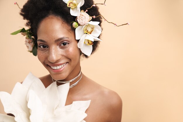 Portrait de jeune femme afro-américaine aux taches de rousseur à moitié nue posant avec des fleurs