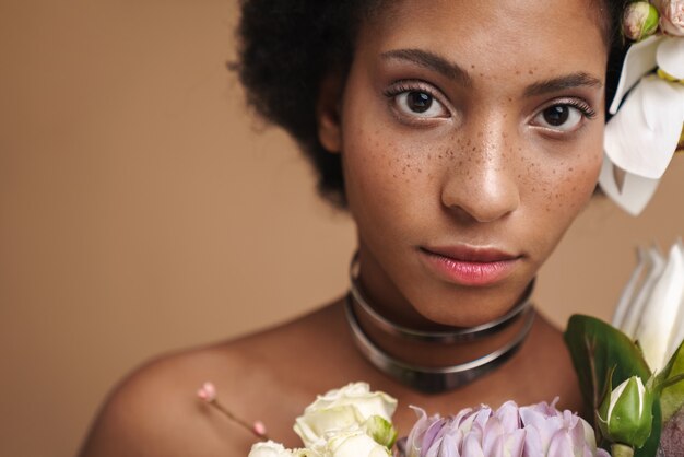 Photo portrait de jeune femme afro-américaine aux taches de rousseur à moitié nue posant avec des fleurs