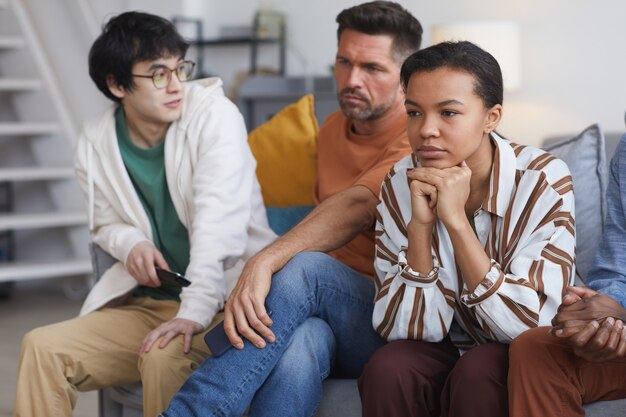 Portrait de jeune femme afro-américaine regardant la télévision à la maison avec des amis, espace de copie