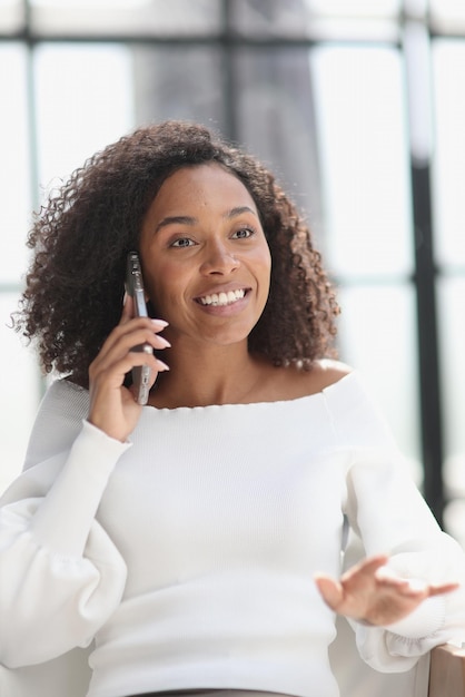 Portrait d'une jeune femme afro-américaine séduisante à l'aide d'un smartphone