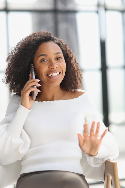 Portrait d'une jeune femme afro-américaine séduisante à l'aide d'un smartphone