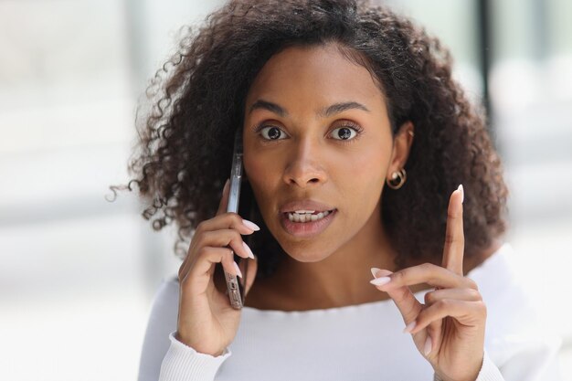 Portrait d'une jeune femme afro-américaine séduisante parlant au téléphone