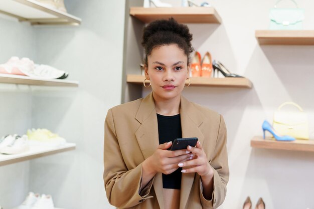 Portrait d'une jeune femme afro-américaine tapant sur son téléphone pendant ses achats