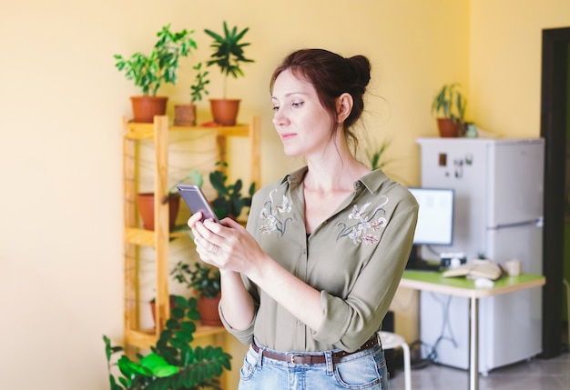 une femme arrose des plantes d'intérieur avec un arrosoir jaune