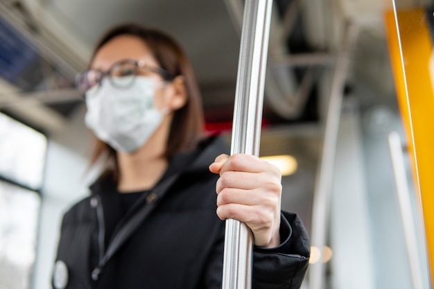 Portrait de jeune femme à l'aide des transports publics avec masque