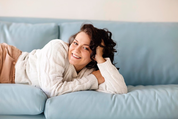 Photo portrait d'une jeune femme allongée sur le canapé à la maison