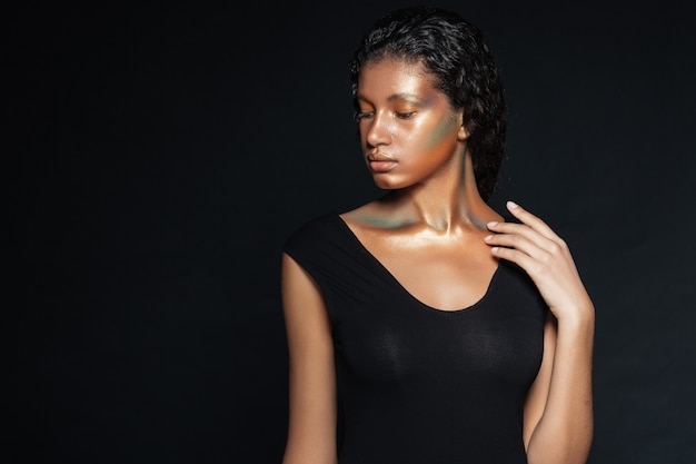 Portrait de jeune femme américaine attirante avec le maquillage de mode au-dessus du noir