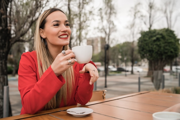 Portrait de jeune femme appréciant et buvant une tasse de café au café. Concept de mode de vie.