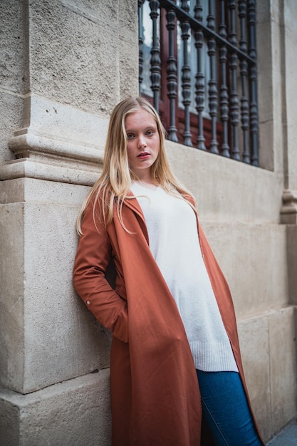 Portrait de jeune femme appuyée contre le mur de la ville Elle regarde la caméra