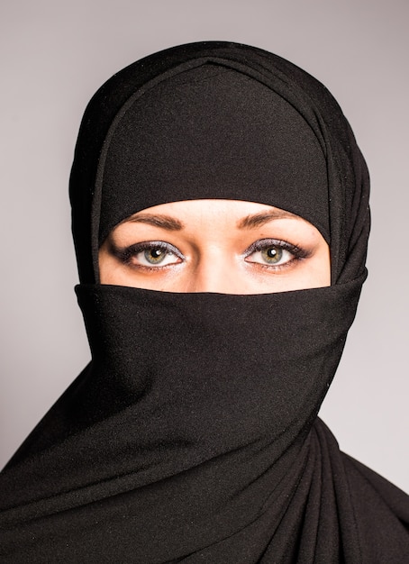 Portrait d'une jeune femme arabe avec ses beaux yeux bleus en niqab en tissu islamique traditionnel.