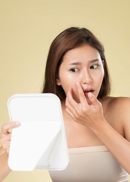 Portrait d'une jeune femme asiatique ardente regardant dans le miroir s'inquiéter des boutons sur son visage Soins de beauté pour les problèmes de peau concept de traitement de l'acné