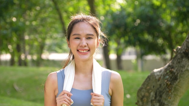 Portrait d'une jeune femme asiatique attrayante souriante et utilisant une serviette blanche se reposant après l'entraînement Souriante