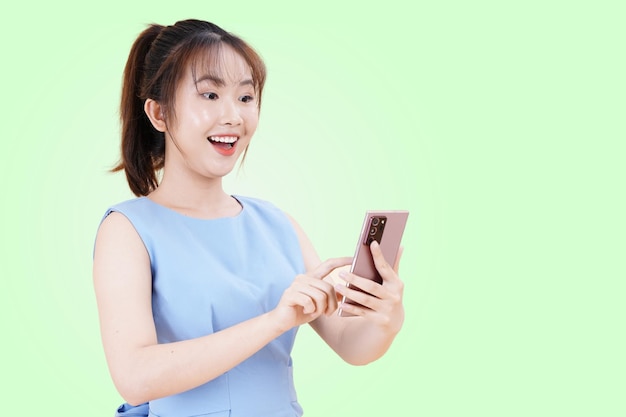 Portrait d'une jeune femme asiatique belle et joyeuse à l'aide d'un téléphone intelligent isolé sur fond de couleur studio