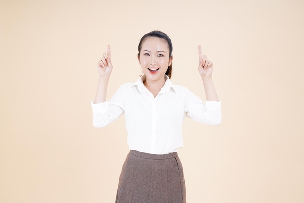Portrait d'une jeune femme asiatique belle et joyeuse pointant du doigt avec un geste de la main isolé sur fond