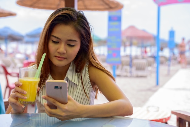 Portrait de jeune femme asiatique belle touriste assis au restaurant au bord de la plage en plein air