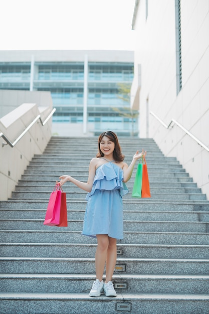 Portrait de jeune femme asiatique descendant avec un sac de couleur