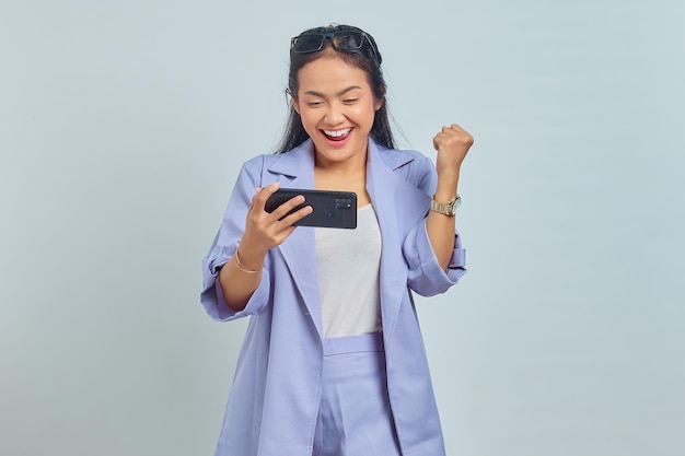 Portrait de jeune femme asiatique excitée regardant la vidéo en streaming sur mobile sur fond blanc