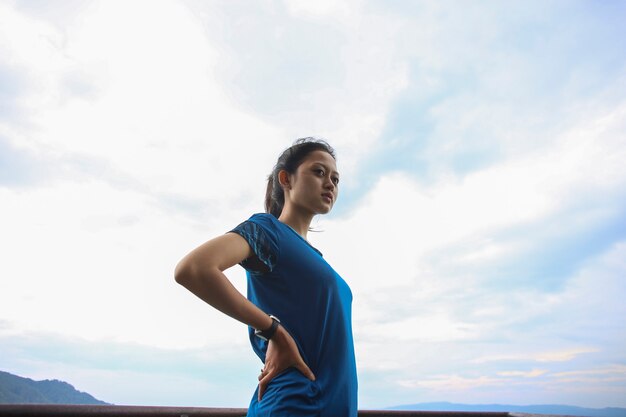 Portrait de jeune femme asiatique en forme et sportive faisant des étirements sur la montagne.