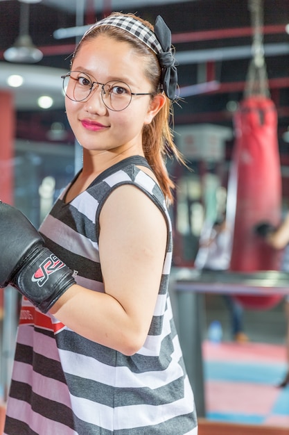 portrait de jeune femme asiatique avec des gants de boxe pratiquant la boxe dans la salle de gym.