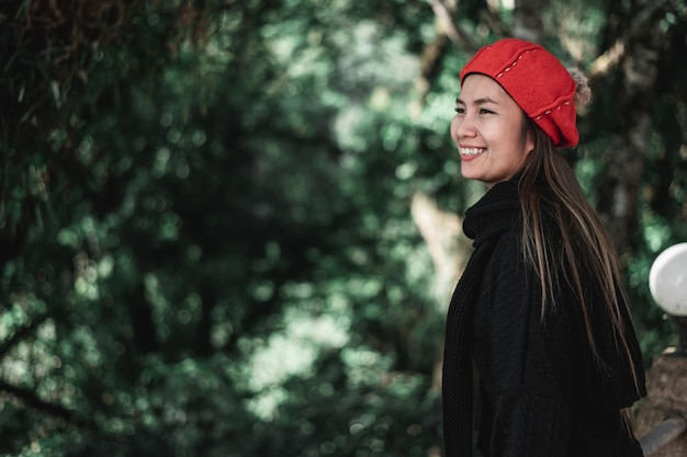 Portrait d'une jeune femme asiatique heureuse en costume d'hiver dans la forêt avec espace de copie Concept de vacances et de voyage