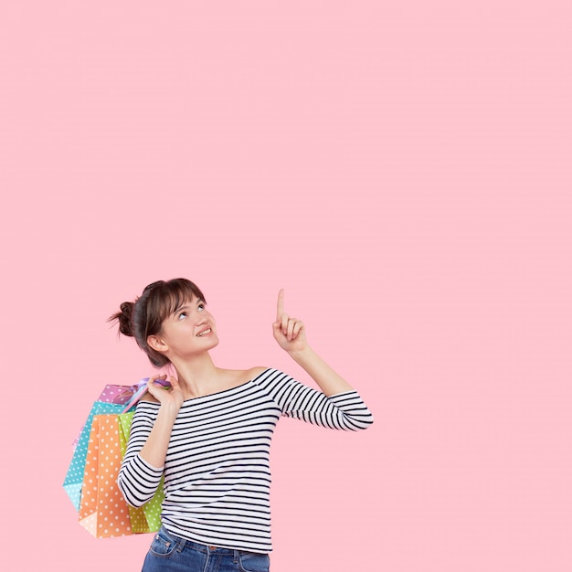 Portrait d'une jeune femme asiatique heureuse avec des sacs à provisions montre sur une place vide pour le texte.