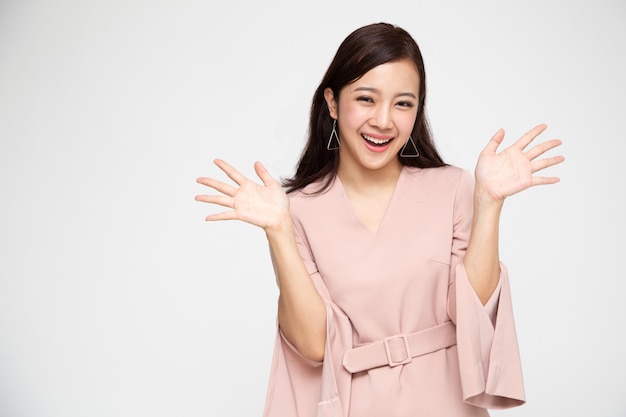 Portrait de jeune femme asiatique hurlant excité debout en robe rose isolé, Wow et concept surpris