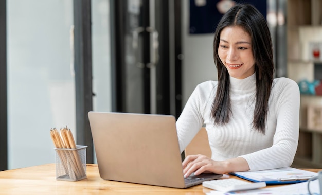 Portrait d'une jeune femme asiatique intelligente travaillant en ligne à la maison avec un ordinateur portable