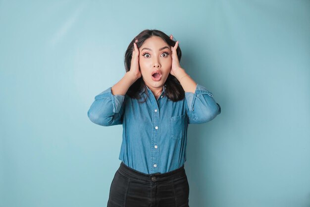 Portrait d'une jeune femme asiatique isolée par un fond bleu se sentant frustrée par l'expression du visage impuissant